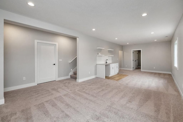 unfurnished living room with light carpet and sink