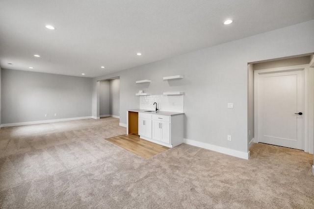 unfurnished living room featuring sink and light carpet