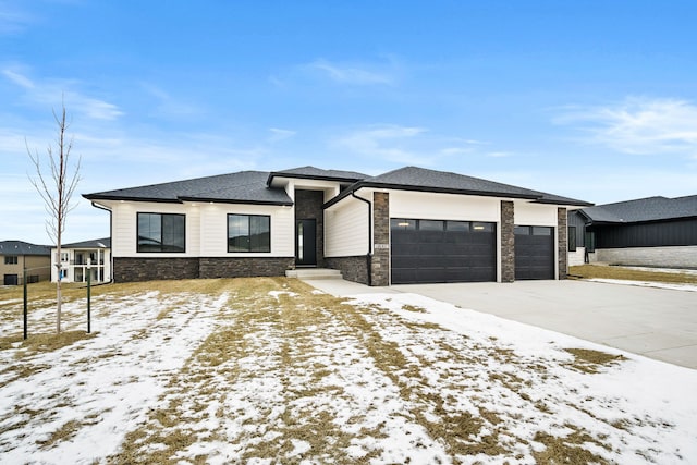 prairie-style house featuring a garage, concrete driveway, and stone siding