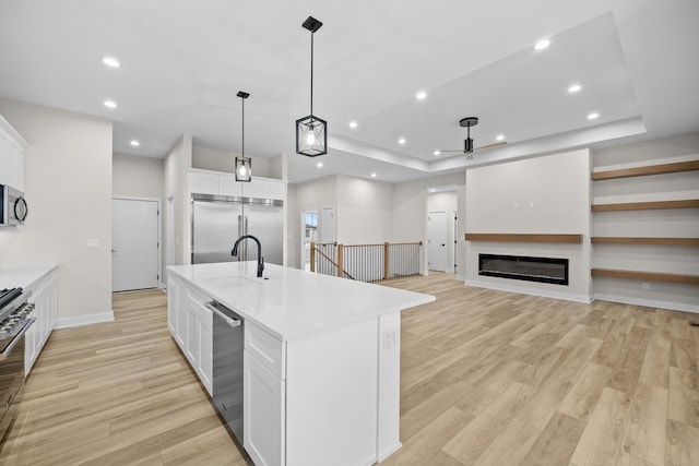 kitchen with light wood-type flooring, white cabinetry, appliances with stainless steel finishes, and a sink