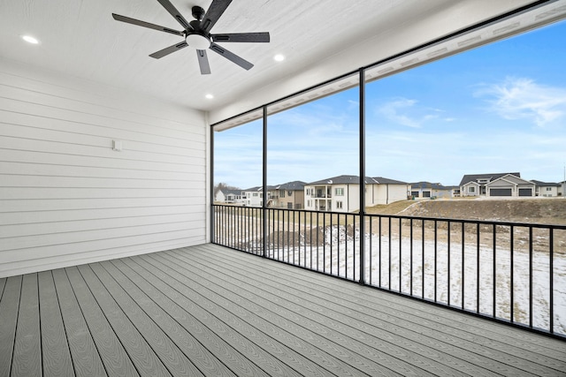 unfurnished sunroom featuring a ceiling fan and a residential view