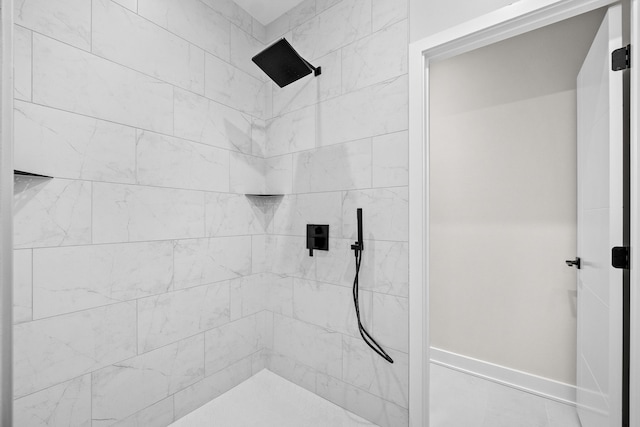 full bathroom featuring tiled shower and baseboards