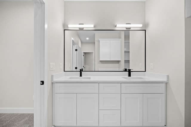 full bathroom featuring double vanity, a sink, and baseboards