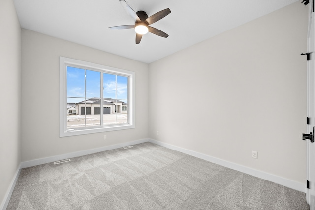 carpeted spare room featuring visible vents, ceiling fan, and baseboards