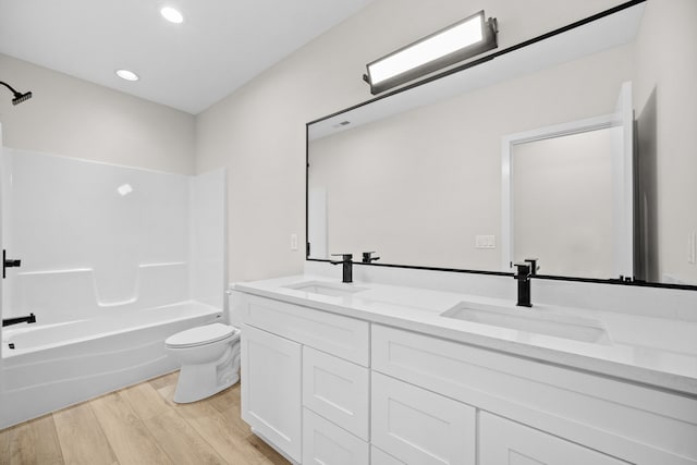 bathroom with double vanity, wood finished floors, a sink, and toilet