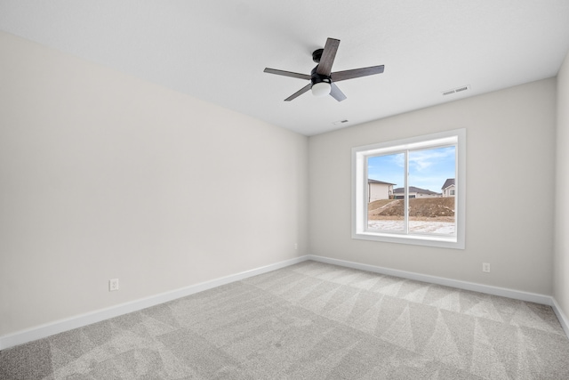 empty room featuring ceiling fan, carpet, visible vents, and baseboards