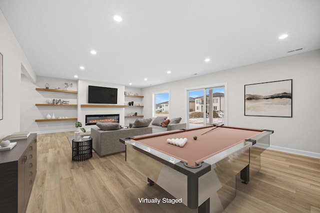 rec room featuring light wood-style floors, recessed lighting, baseboards, and a glass covered fireplace