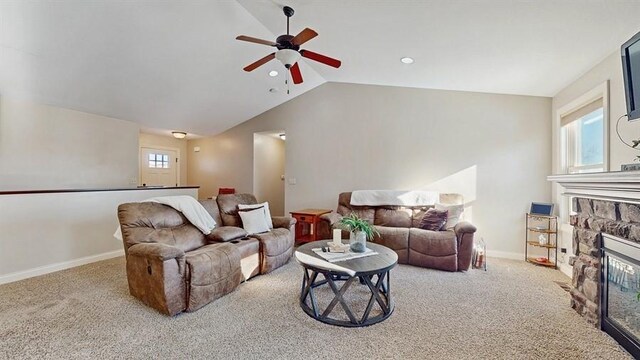 carpeted living room featuring ceiling fan, a stone fireplace, and vaulted ceiling