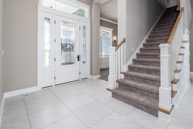 foyer featuring light tile patterned flooring and crown molding