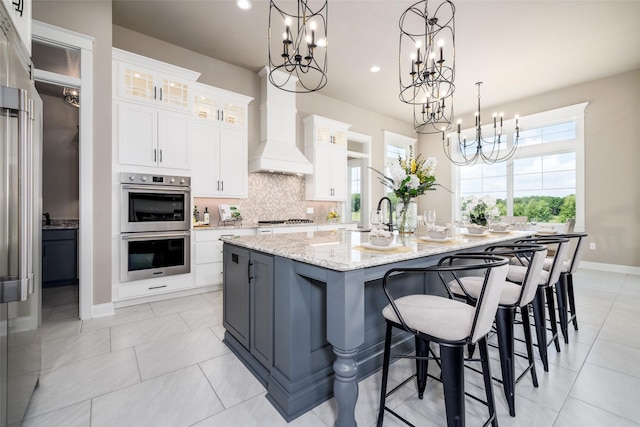 kitchen featuring decorative light fixtures, a large island, white cabinetry, and double oven