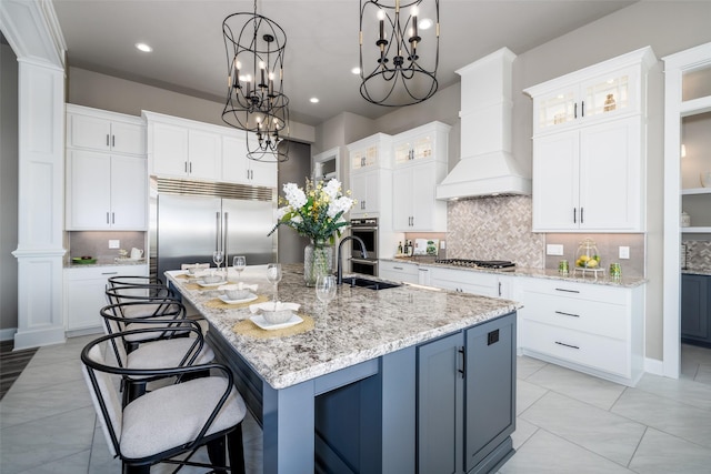 kitchen with custom range hood, white cabinetry, a large island, and appliances with stainless steel finishes