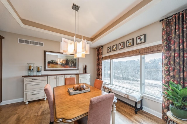 dining space featuring light wood-type flooring, a tray ceiling, and a wealth of natural light