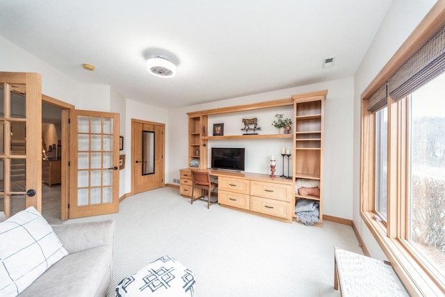 living room featuring built in desk, french doors, and light carpet