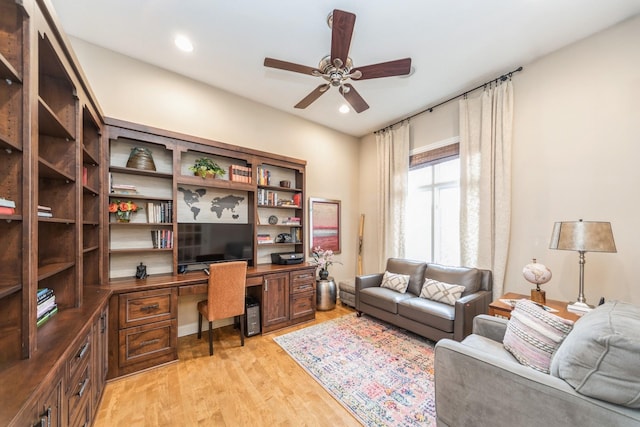 office featuring built in desk, ceiling fan, and light hardwood / wood-style flooring