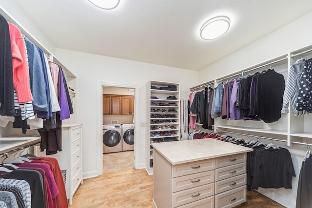 walk in closet with light hardwood / wood-style flooring and washing machine and clothes dryer