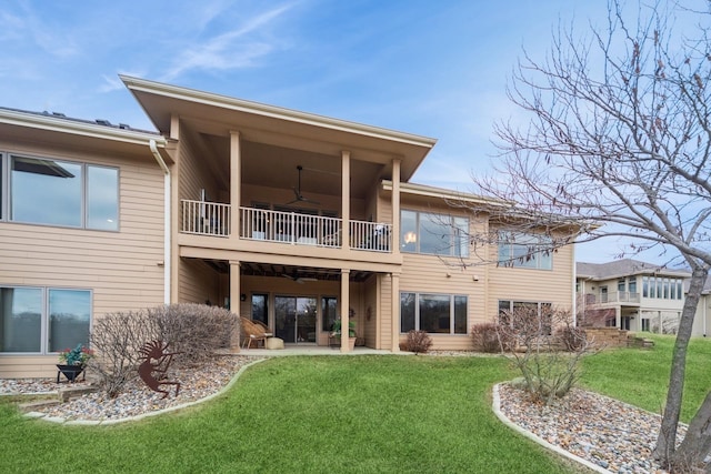 rear view of property with a balcony, a patio, ceiling fan, and a lawn