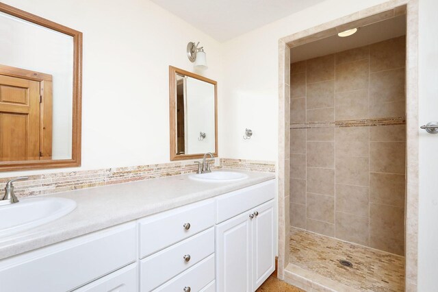 bathroom with a tile shower and vanity