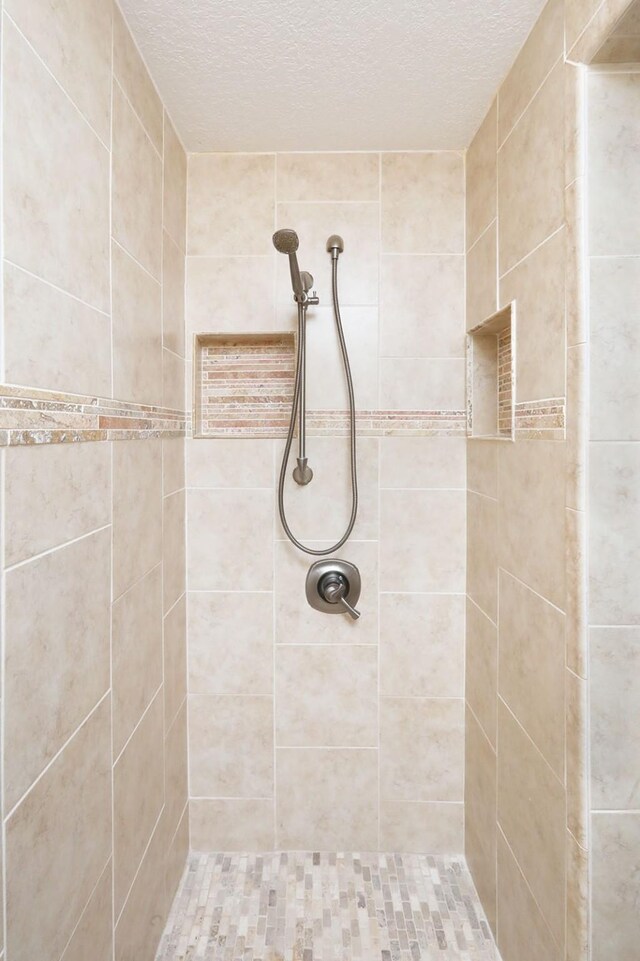 bathroom with tiled shower and a textured ceiling