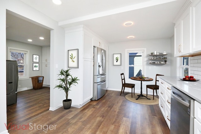 kitchen featuring stainless steel appliances, white cabinets, light stone countertops, and dark wood-type flooring