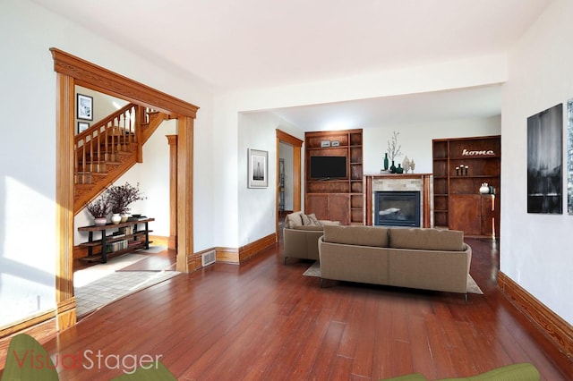 living room with dark wood-type flooring and a tile fireplace