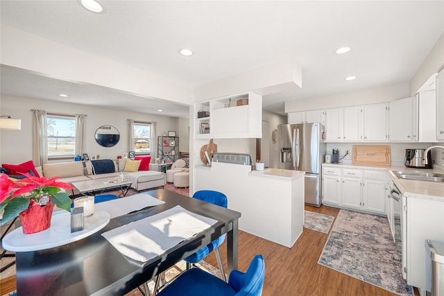 kitchen with sink, white cabinets, light hardwood / wood-style floors, and stainless steel fridge with ice dispenser