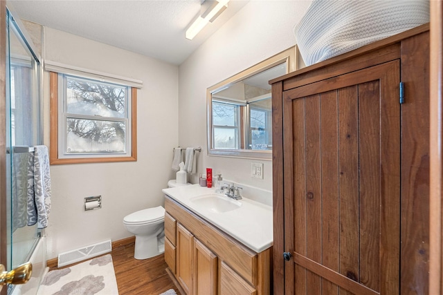 full bathroom with enclosed tub / shower combo, hardwood / wood-style floors, vanity, and toilet