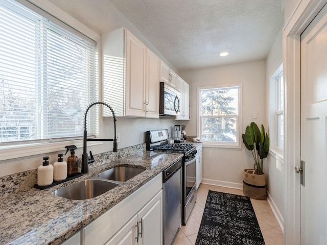 kitchen featuring sink, light stone counters, white cabinets, and appliances with stainless steel finishes