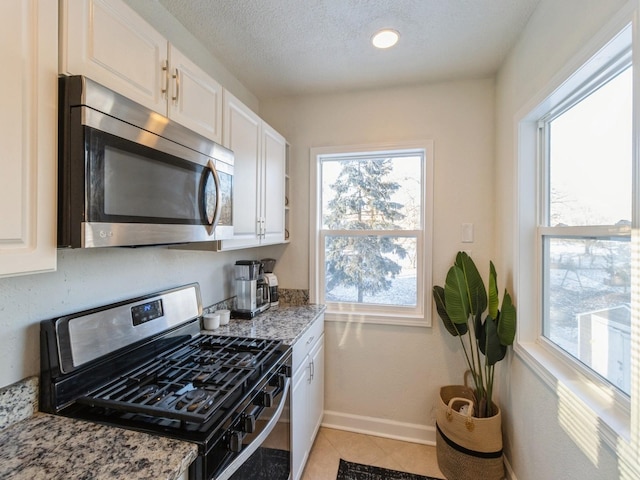 kitchen with light stone countertops, white cabinetry, and stainless steel appliances