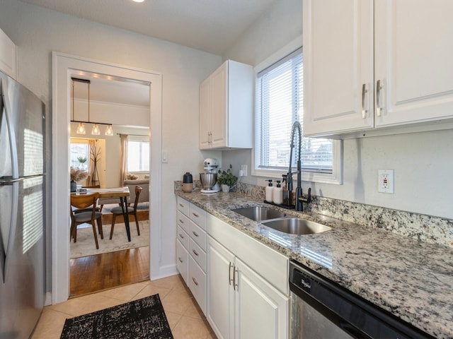 kitchen featuring light stone countertops, appliances with stainless steel finishes, white cabinets, sink, and light tile patterned flooring