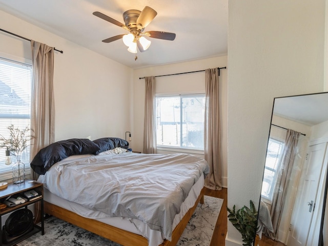 bedroom with multiple windows, hardwood / wood-style flooring, and ceiling fan