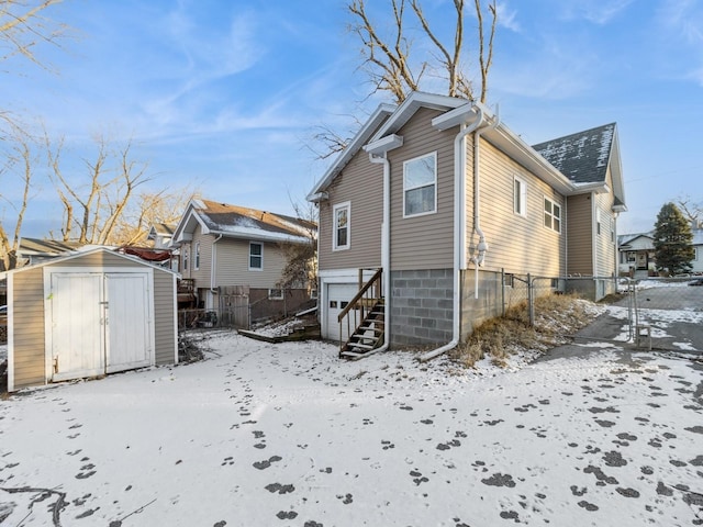 snow covered rear of property featuring a shed