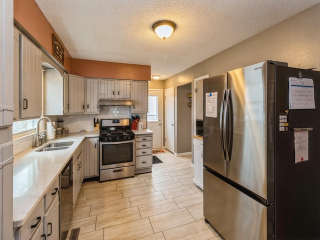 kitchen featuring stainless steel appliances, a textured ceiling, sink, and backsplash