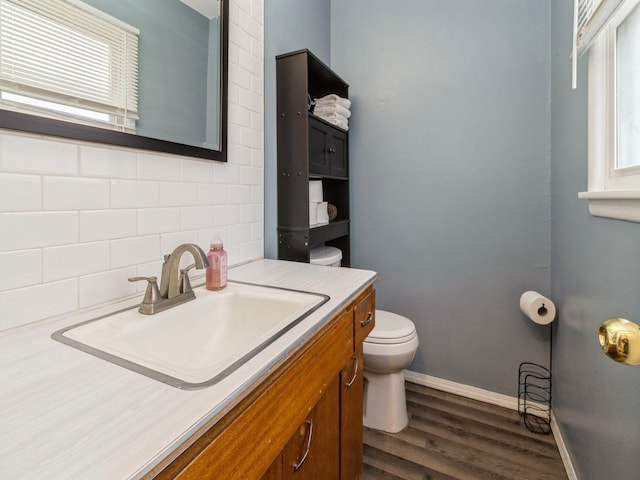 bathroom featuring toilet, wood-type flooring, tasteful backsplash, and vanity