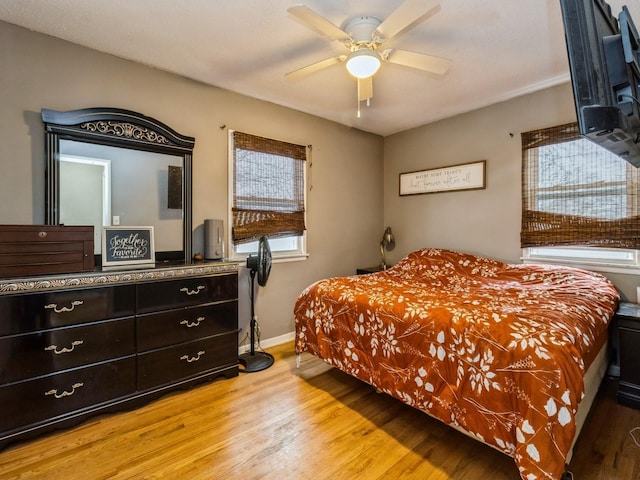 bedroom with multiple windows, ceiling fan, and light wood-type flooring