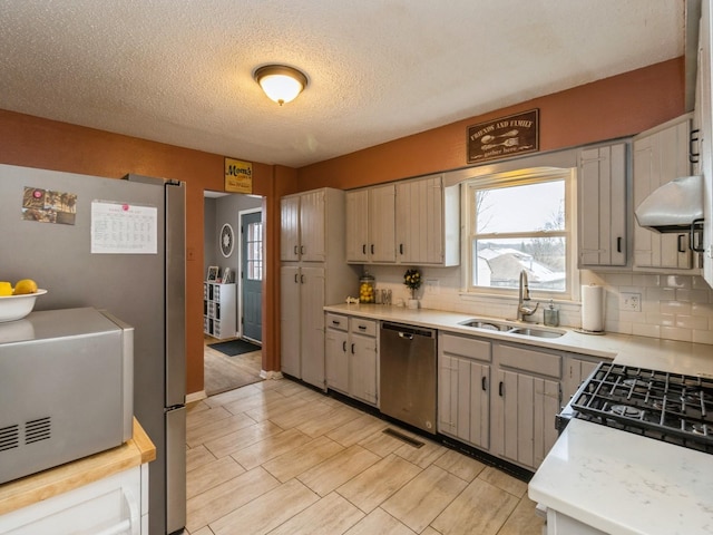 kitchen with sink, stainless steel appliances, backsplash, and a textured ceiling