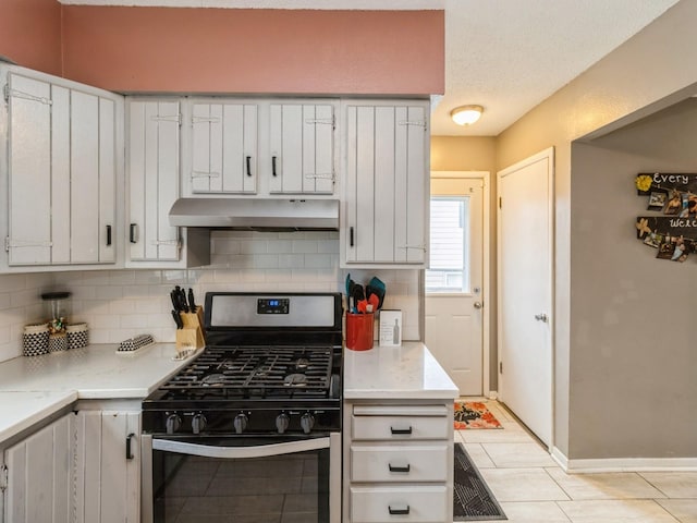 kitchen with stainless steel gas range, light tile patterned floors, a textured ceiling, white cabinetry, and backsplash