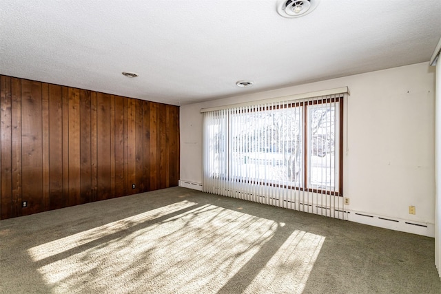 empty room with wooden walls, baseboard heating, and carpet