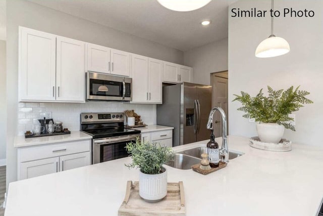 kitchen featuring hanging light fixtures, tasteful backsplash, white cabinetry, appliances with stainless steel finishes, and sink