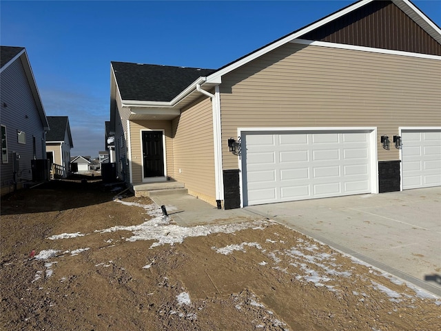 view of snow covered exterior with cooling unit and a garage