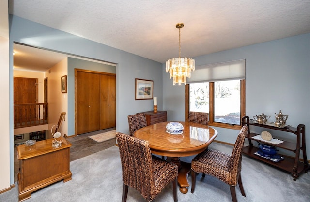 dining area featuring an inviting chandelier, a textured ceiling, and carpet flooring