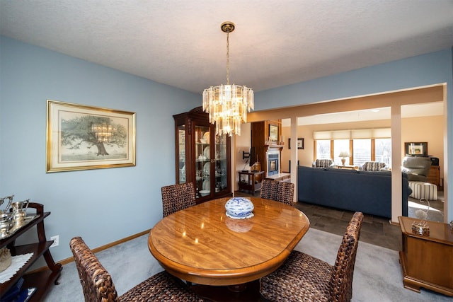 dining area featuring an inviting chandelier, a textured ceiling, and dark colored carpet