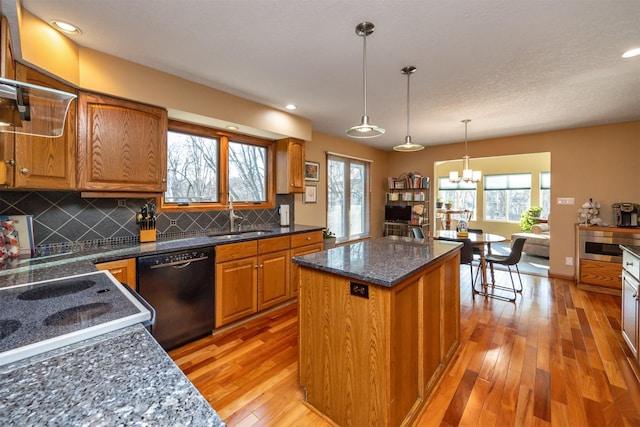 kitchen featuring dishwasher, pendant lighting, a kitchen island, sink, and tasteful backsplash