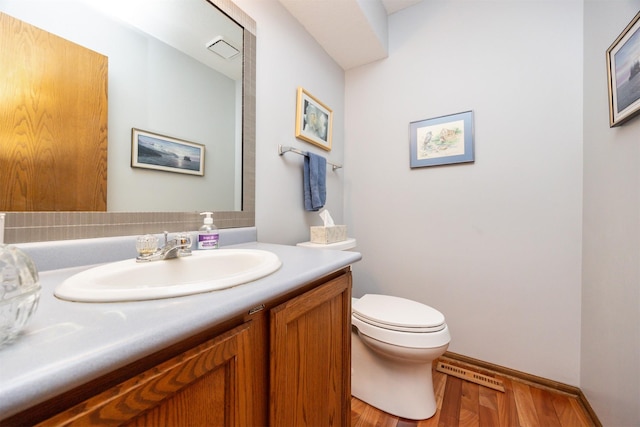 bathroom with toilet, vanity, and hardwood / wood-style floors