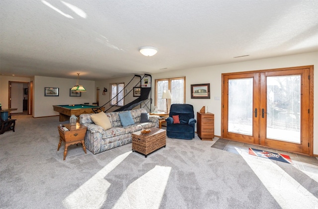 carpeted living room with french doors, billiards, and a textured ceiling