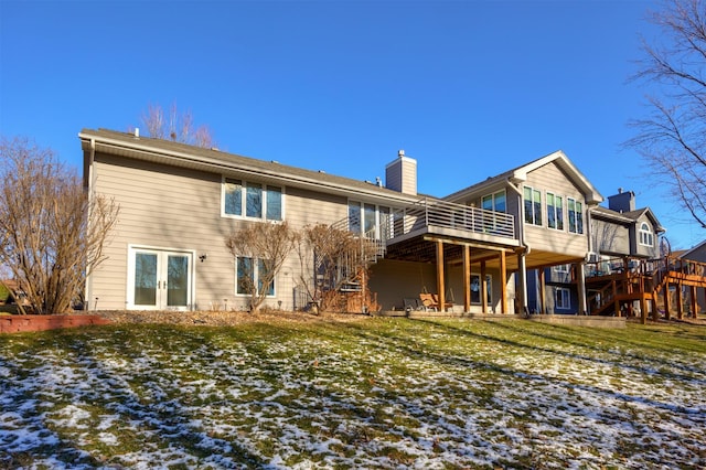 snow covered rear of property featuring a deck and a lawn