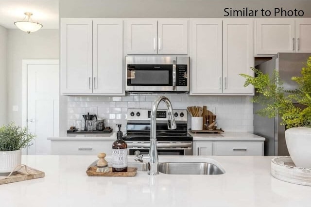 kitchen featuring white cabinets, stainless steel appliances, and decorative backsplash