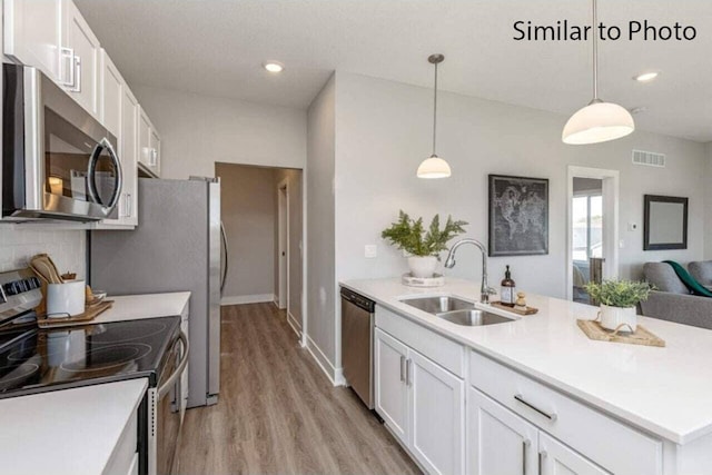 kitchen with decorative light fixtures, stainless steel appliances, white cabinets, and sink