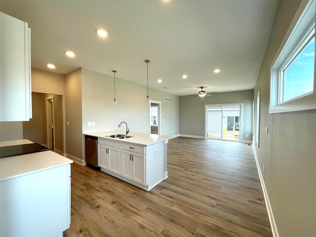 kitchen with sink, light hardwood / wood-style flooring, dishwasher, hanging light fixtures, and white cabinets