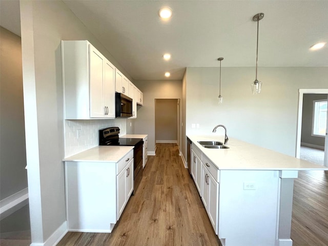 kitchen with sink, hanging light fixtures, electric range, white cabinets, and kitchen peninsula