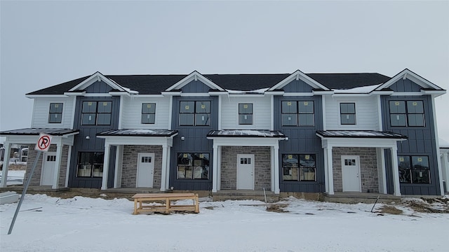 townhome / multi-family property with a standing seam roof, stone siding, board and batten siding, and metal roof